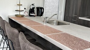 A modern kitchen with a stainless steel sink, a coffee maker, and a kettle on the countertop. - Vakantiepark de Zeeuwse Parel - Noordzee Deluxe by Interhome (Scherpenisse)