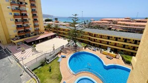 A hotel with a swimming pool, multiple balconies, and a view of the sea. - Torres del Sol (Arona)
