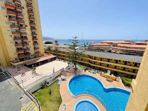 A hotel with a swimming pool, multiple balconies, and a view of the sea. - Torres del Sol (Arona)