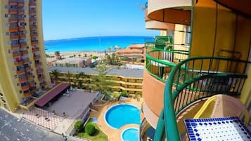 Un hotel moderno con piscina, vistas a la playa y un balcón con una silla.