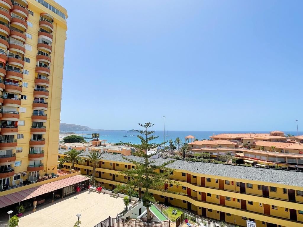 Hotel frente al mar con varios balcones, piscina y vista al mar y embarcaciones.