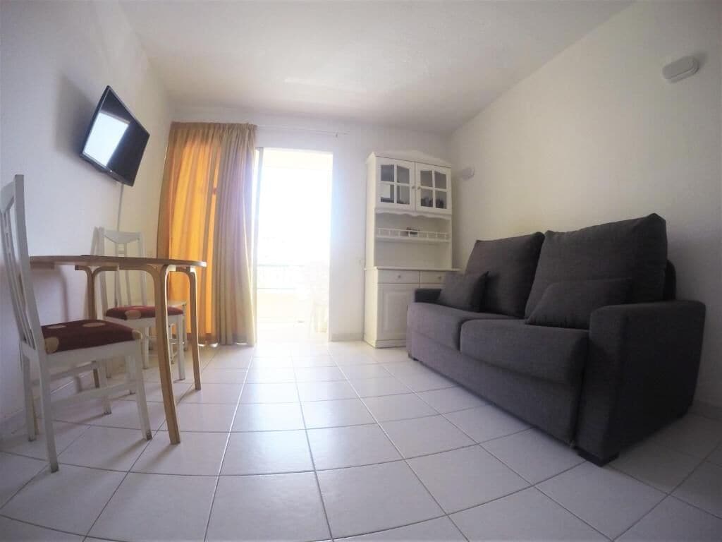 Una sala de estar con sofá, sillas, televisor y aparador.