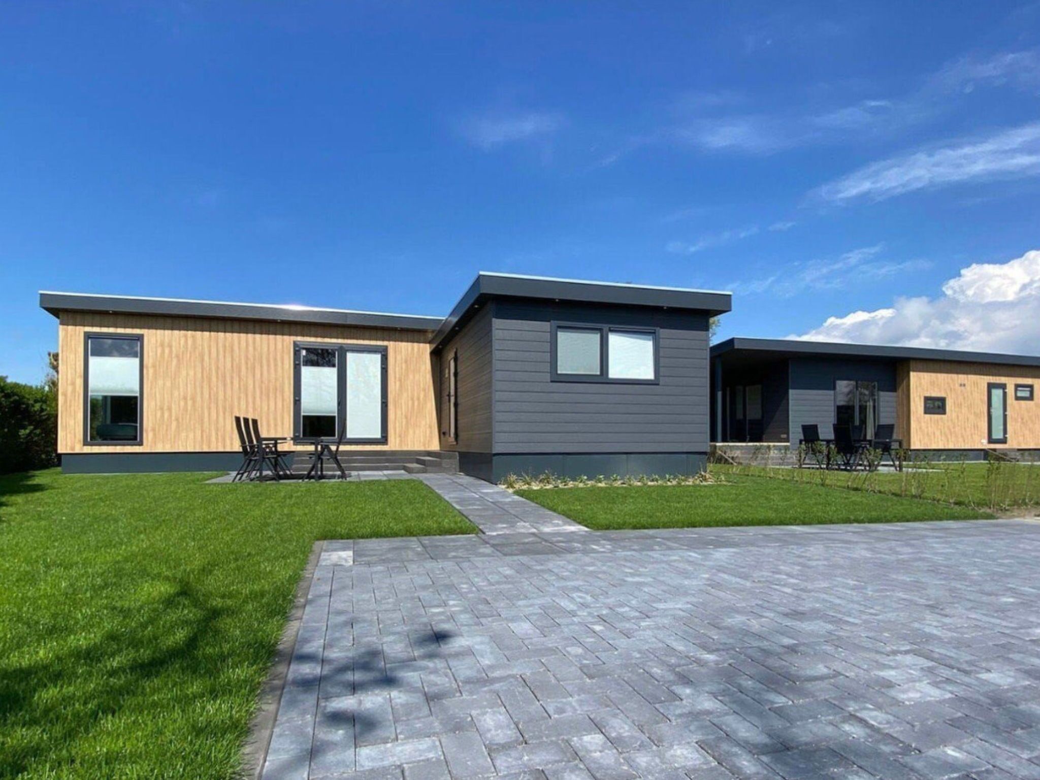 A modern two-story house with a paved driveway and a grassy lawn.