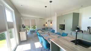 A modern kitchen with a long island, blue chairs, and pendant lighting. - Vakantiepark de Zeeuwse Parel - de Schelde by Interhome (Scherpenisse)