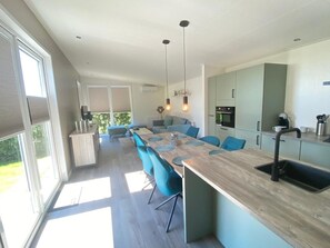 A modern kitchen with a long island, blue chairs, and pendant lighting. - Vakantiepark de Zeeuwse Parel - de Schelde by Interhome (Scherpenisse)
