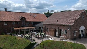 A courtyard with outdoor seating and a brick building with a tiled roof. - Recreatieboerderij Tergracht - D'r Wesjzulder by Interhome (Epen)