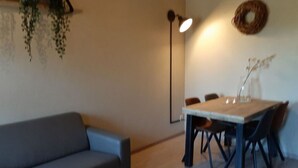 A living room with a sofa, a dining table with chairs, a floor lamp, and a wall-mounted wreath. - Recreatieboerderij Tergracht - t Schob by Interhome (Epen)