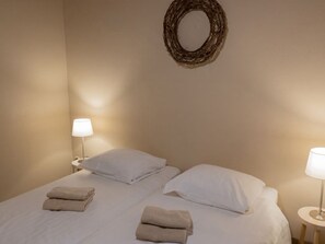 Ein Hotelzimmer mit einem Bett, zwei Nachttischlampen und einem an der Wand befestigten Kranz.