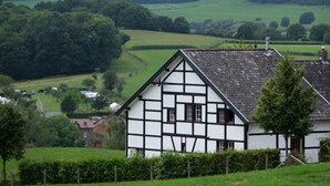 A traditional half-timbered house with a sloped roof, surrounded by lush green fields and trees. - Recreatieboerderij Tergracht - t Schob by Interhome (Epen)