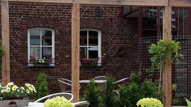 A two-story brick building with multiple windows, a balcony, and outdoor seating. - Recreatieboerderij Tergracht - t Schob by Interhome (Epen)