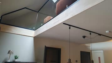 A modern interior with a glass ceiling, wooden beams, and pendant lighting.