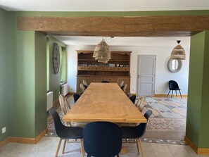 Ein Essbereich mit einem Holztisch, schwarzen Stühlen, einem gemusterten Boden und einer Holztruhe mit Gläsern.