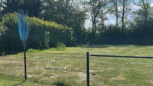 A fenced outdoor area with a grassy field and trees in the background. - Beach Resort Kamperland - 1123 by Interhome (Kamperland)