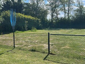 Ein von einer Hecke umgebener Außenbereich mit einer Rasenfläche und Bäumen im Hintergrund.
