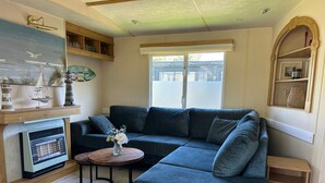A living room with a sectional sofa, a small round table with a vase, and a fireplace. - Beach Resort Kamperland - 1123 by Interhome (Kamperland)