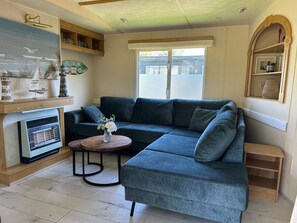 Ein Wohnzimmer mit einer Eckcouch, einem kleinen runden Tisch mit einer Vase und einem Kamin.