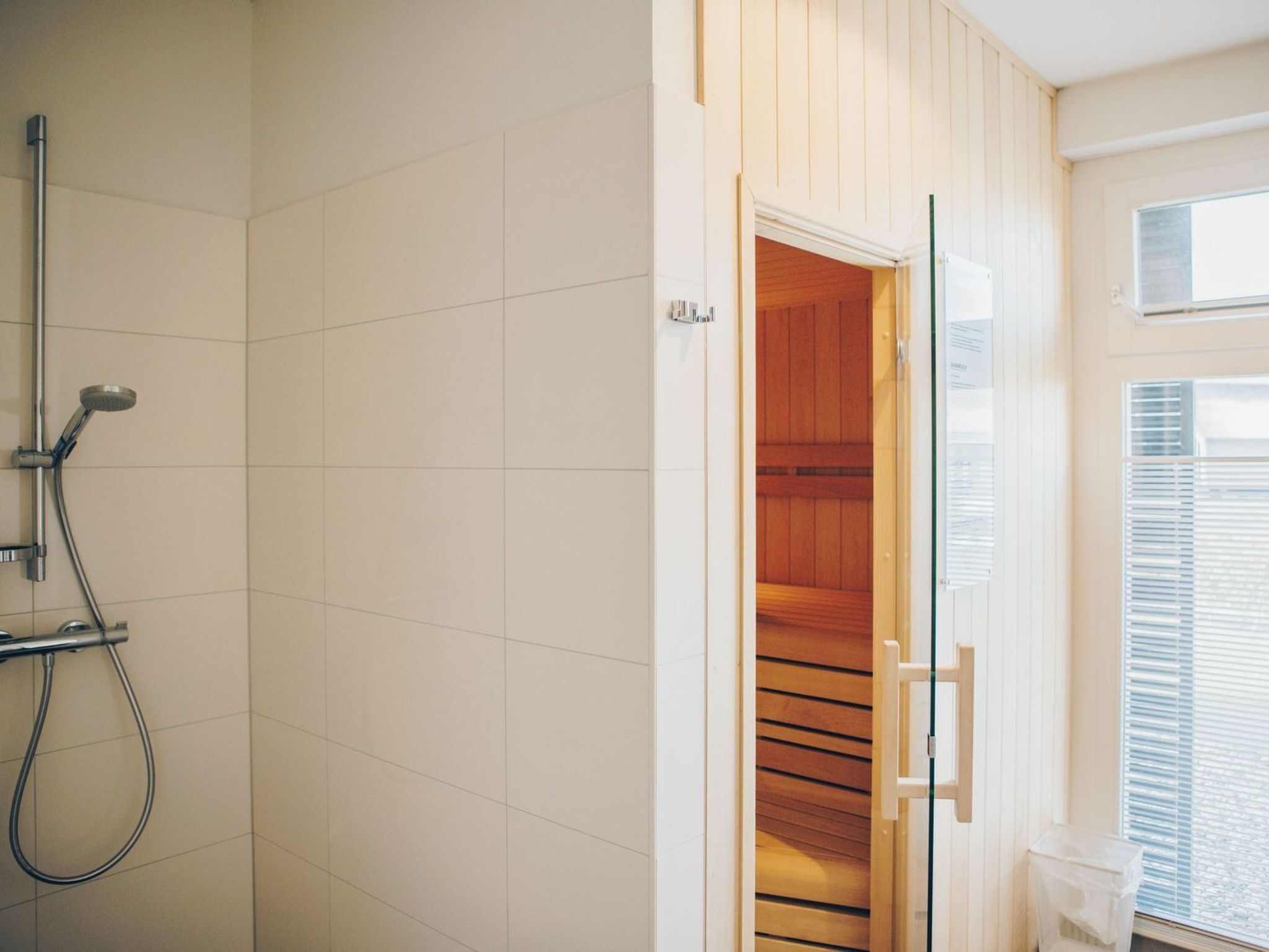 Ein Badezimmer mit Dusche, einem Holzschrank und einem Fenster mit Jalousien.
