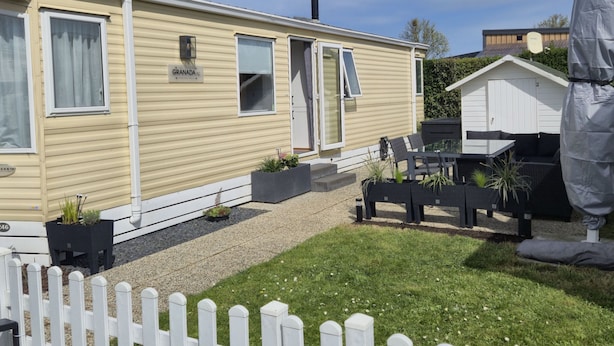 A mobile home with a patio area, outdoor seating, and a fenced garden. - Beach Resort Kamperland - 246 by Interhome (Kamperland)