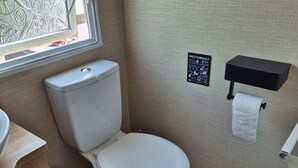 A compact bathroom with a toilet, a trash bin, a sink, and a window. - Beach Resort Kamperland - 246 by Interhome (Kamperland)