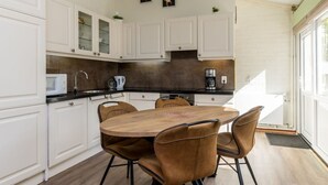 Eine moderne Küche mit weißen Schränken, einem runden Holztisch und vier braunen Stühlen.