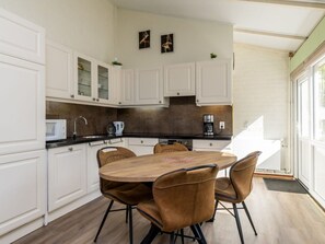 A modern kitchen with white cabinets, a round wooden table, and four brown chairs. - Bungalowpark Simpelveld - Schakel 23 by Interhome (Simpelveld)