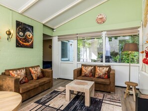 A living room with two sofas, a coffee table, a painting, and a clock on the wall. - Bungalowpark Simpelveld - Schakel 23 by Interhome (Simpelveld)