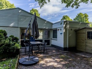 A patio area with a table and chairs, a swing, and a small shed. - Bungalowpark Simpelveld - Schakel 23 by Interhome (Simpelveld)
