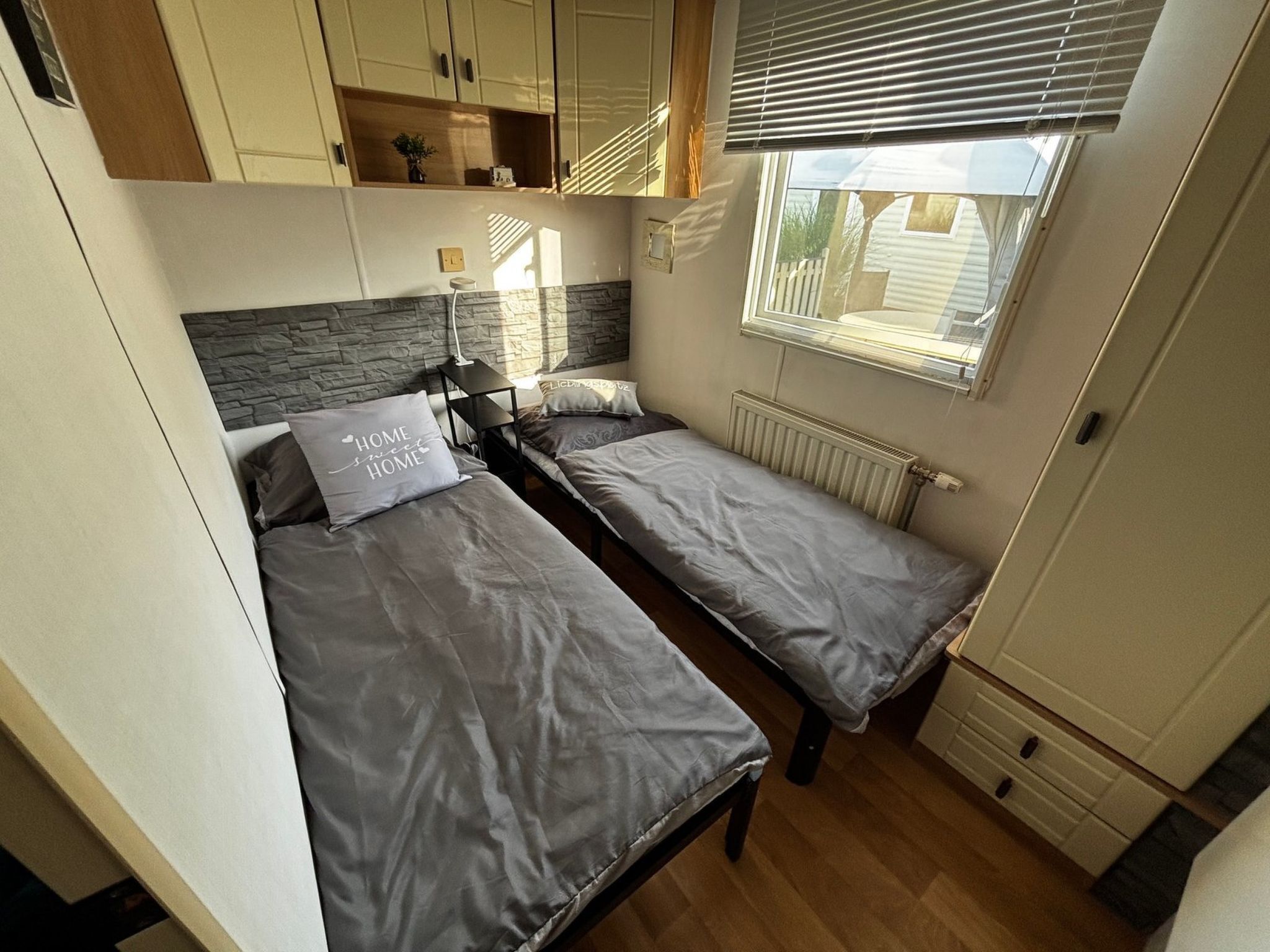 Ein gemütliches Schlafzimmer mit zwei Einzelbetten, einem kleinen Tisch und einem Fenster mit Jalousien.