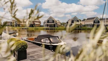 Un canal con casas en la orilla opuesta, una barca amarrada al muelle y un cielo despejado.