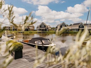 A canal with houses on the opposite bank, a boat docked on the pier, and a clear sky.