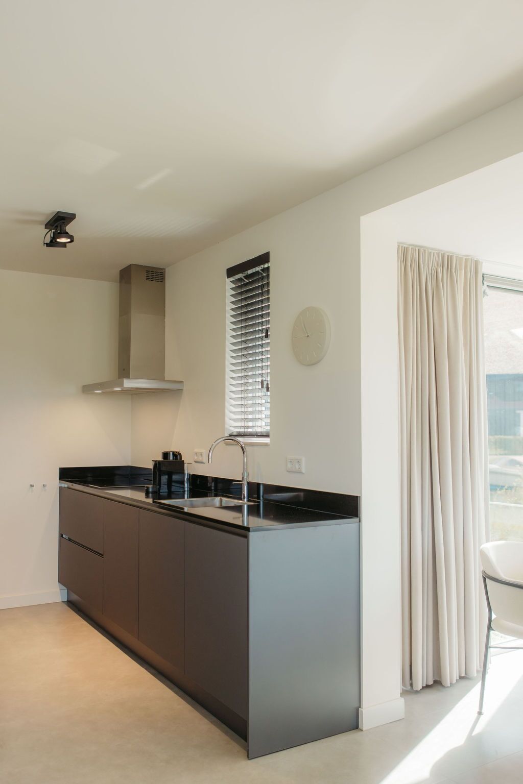 Una cocina moderna con una isla central, horno empotrado y ventana con persianas.