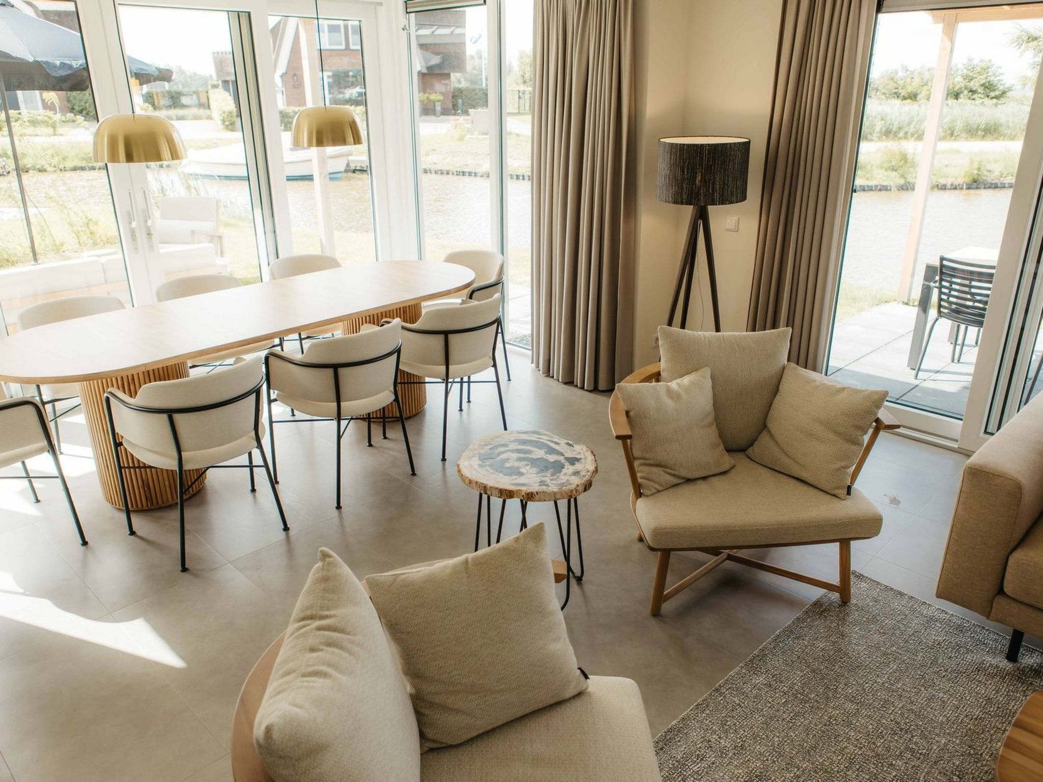 Una sala moderna con un sofá, sillones, una mesa de centro y un comedor con sillas y una mesa.