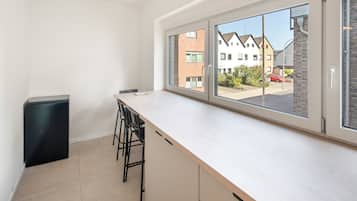 Une cuisine moderne avec une grande fenêtre, une poubelle noire et un tabouret de bar.