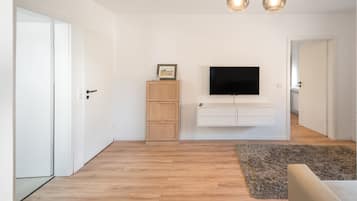Un salon moderne avec un téléviseur à écran plat fixé au mur, un meuble en bois et un tapis moelleux.