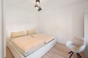 Ein schlicht eingerichtetes Schlafzimmer mit Bett, Stuhl und einer Hängelampe.