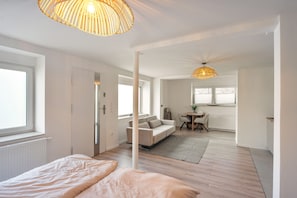 Ein modernes Hotelzimmer mit Bett, einer Sitzecke, einem Essbereich und einem großen Fenster.