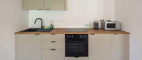 Cocina compacta con lavaplatos, microondas y una pequeña zona de encimera.