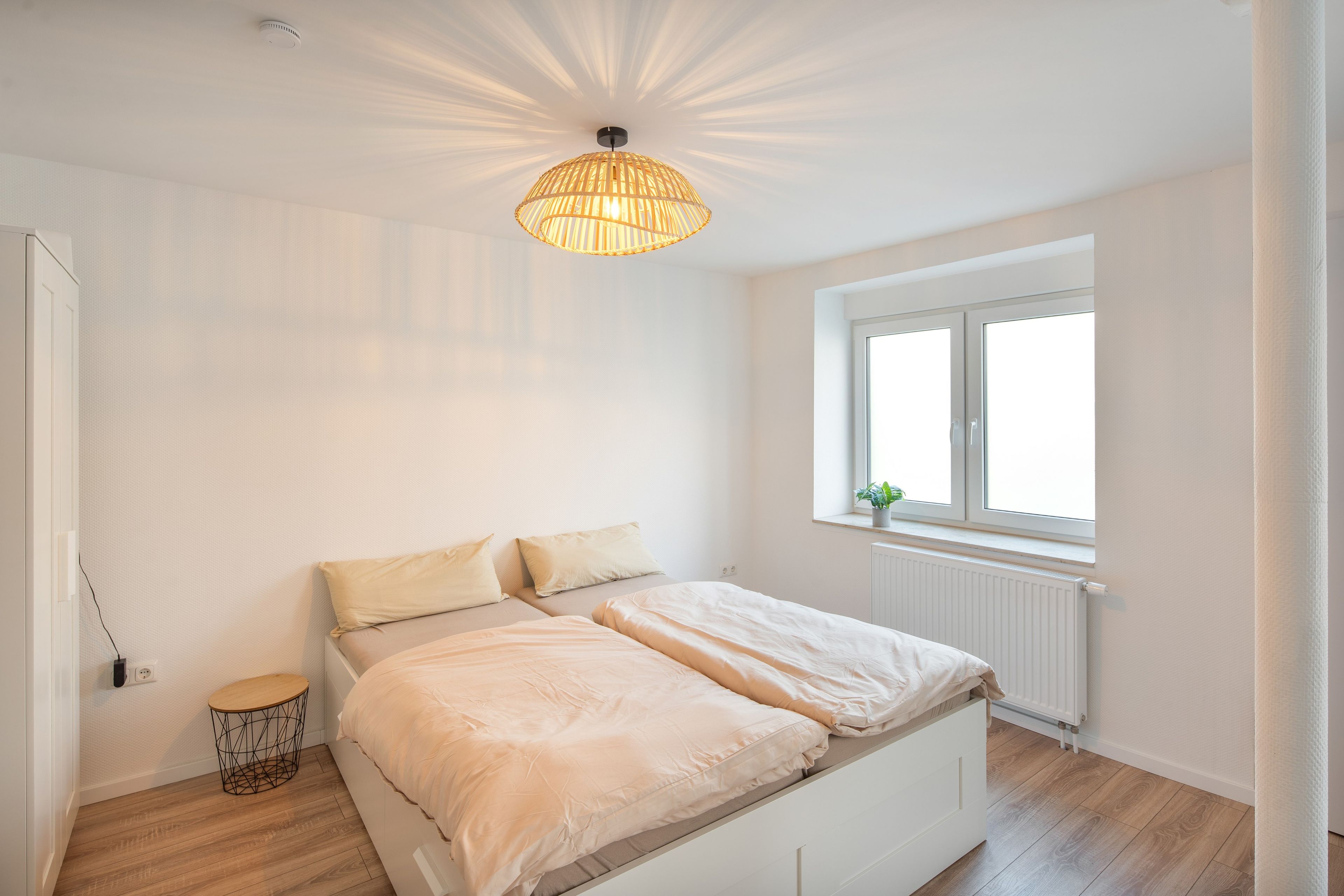 Ein Schlafzimmer mit einem Bett, einem Fenster und einer Deckenleuchte.