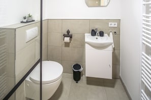 Une petite salle de bain comprenant des toilettes, un lavabo et une petite poubelle.
