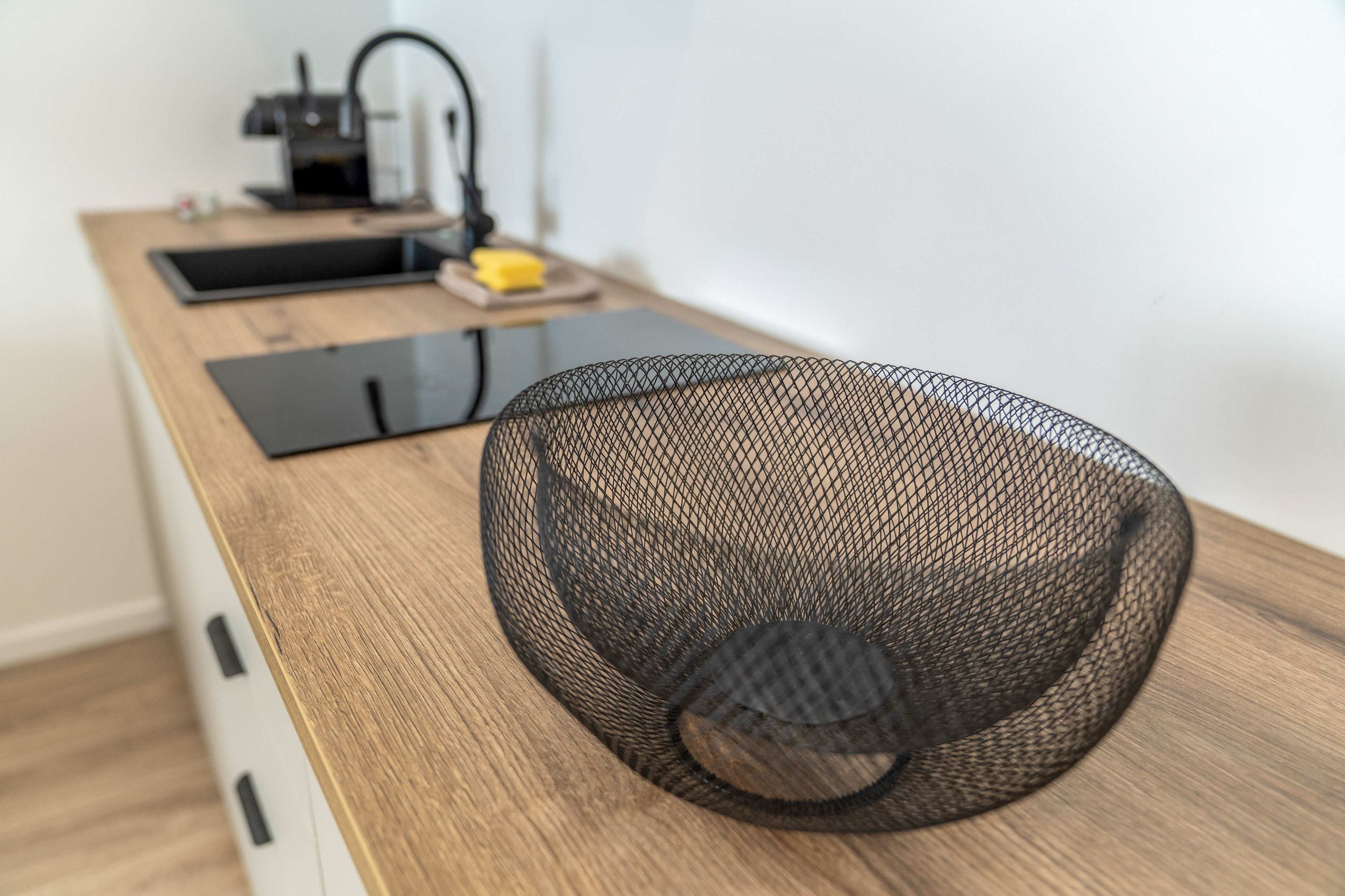 A kitchen counter with a mesh bowl, a coffee machine, and a smartphone.