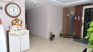 Una habitación con un reloj, una estatua, un armario y plantas en macetas.