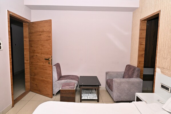 A small, compact room with a bed, two armchairs, a coffee table, and a wardrobe.