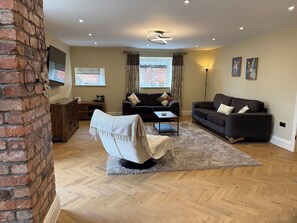 Ein Wohnzimmer mit Ziegelwand, einer Couch, einem Sessel, einem Couchtisch und einer Lampe.