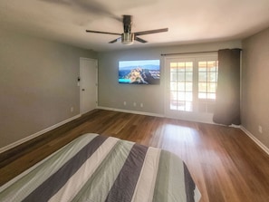 A bedroom with a bed, a ceiling fan, a television, and a window with curtains. - 5 bedrooms 3bath Cozy Home (Warner Robins)