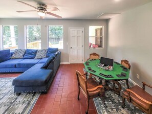 A living room with a blue sofa, a dining table with chairs, a ceiling fan, and a view through the windows. - 5 bedrooms 3bath Cozy Home (Warner Robins)