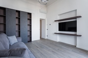 A modern living room with a grey sofa, built-in shelving, and a mounted TV. - Blue Horizon 1 By Dimorra  (Naples)