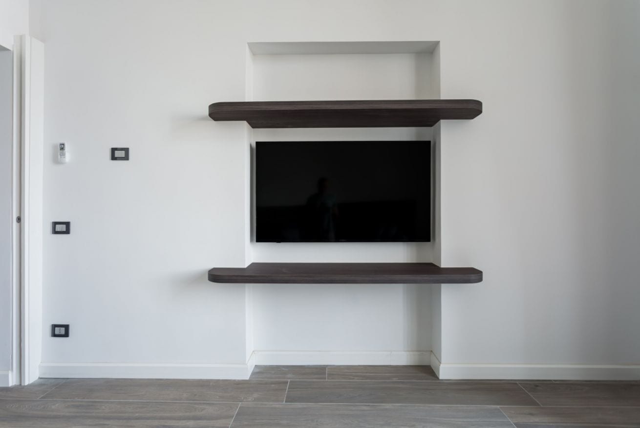 Ein modernes Interieur mit einem wandmontierten Flachbildfernseher, der von zwei dunklen Holzbögen begleitet wird.
