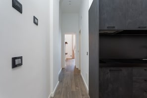 A hallway with a modern kitchen area featuring dark cabinetry and a wooden floor. - Blue Horizon 1 By Dimorra  (Naples)