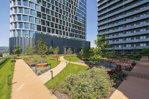 A modern building complex with a curved glass facade, surrounded by landscaped gardens and pathways. - Bright & Stylish Apartment with a Balcony | Parking | Workspace (Katowice)