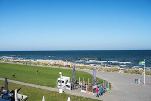 A coastal view with a grassy area, beach umbrellas, and a small kiosk. - Holiday Apartment Strandblick – Sea Views, Relaxation & Holiday Bliss (Schönberg (Holstein))